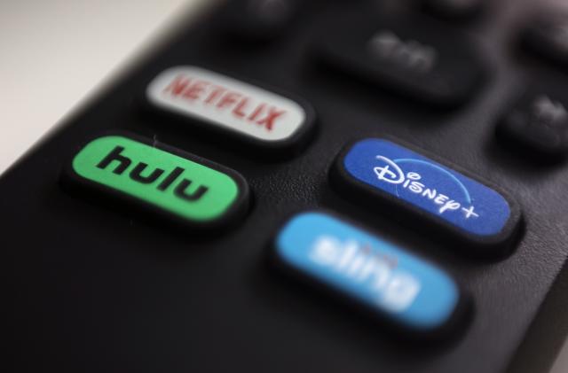 FILE - The logos for streaming services Netflix, Hulu, Disney Plus and Sling TV are pictured on a remote control on Aug. 13, 2020, in Portland, Ore. Walt Disney Co. said it will acquire a 33% stake in Hulu from Comcast for approximately $8.6 billion, a deal that will give Disney undisputed control of the streaming service. (AP Photo/Jenny Kane, File)