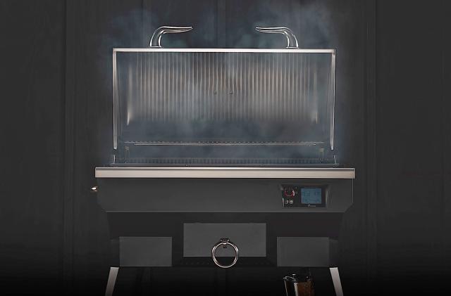 A head-on view of the Recteq SmokeStone 600 grill with its lid open and smoke wafting off the grill surface. Photographed in front of a black background.